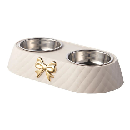Beige pet bowl with gold bow design on a white background